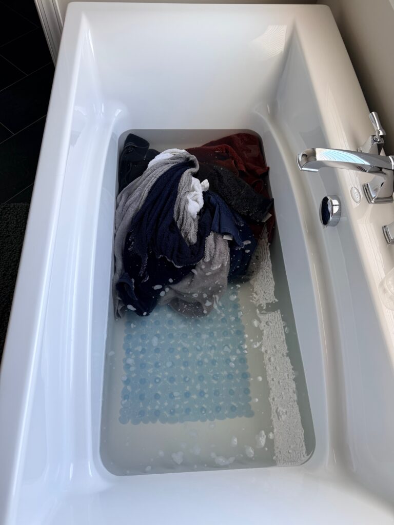 Towels soaking in discolored water for two hours showing detergent and fabric softener buildup being released
